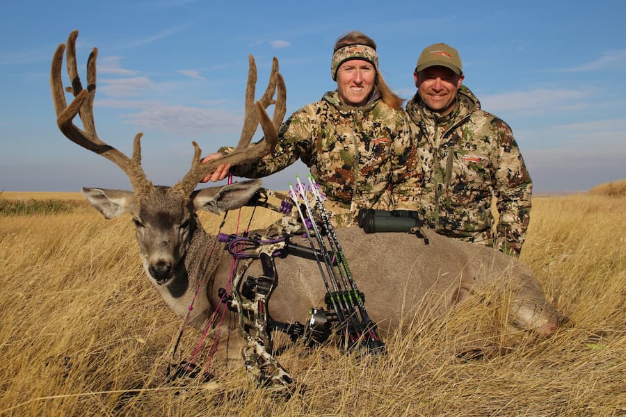 bow hunting couple pose with velvet antlered deer.