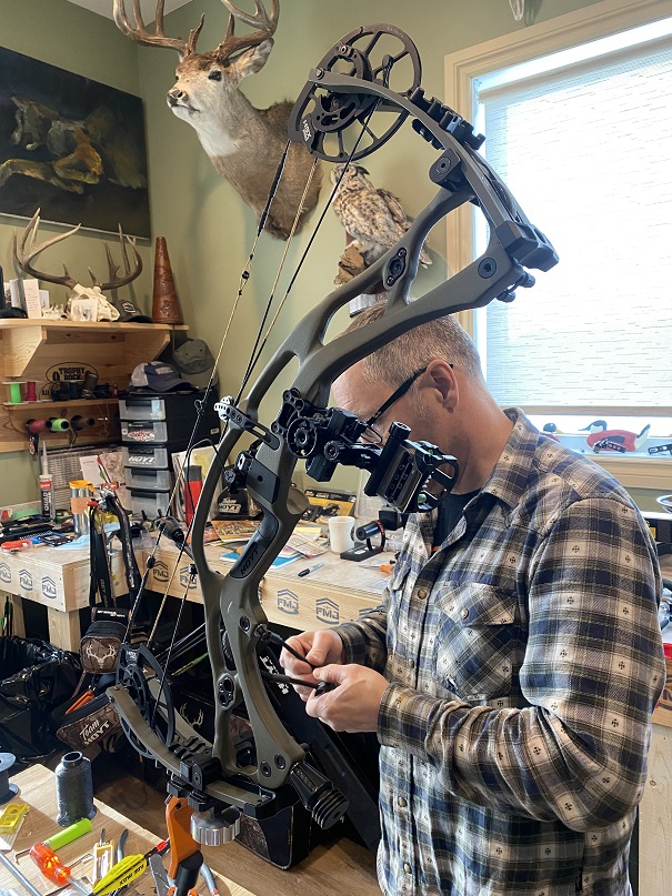 Archer tightening the screws of his compound bow.