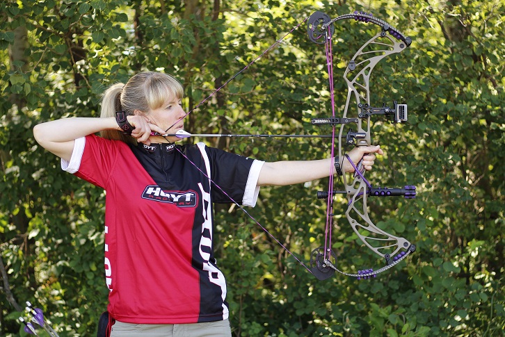 Side view of archer with bow at full draw looking through her sight.