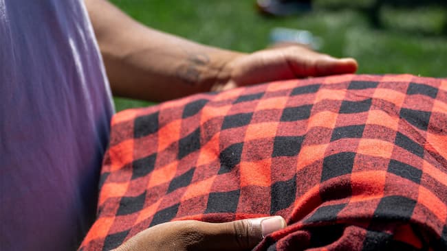 person holding red and black plaid fabric.